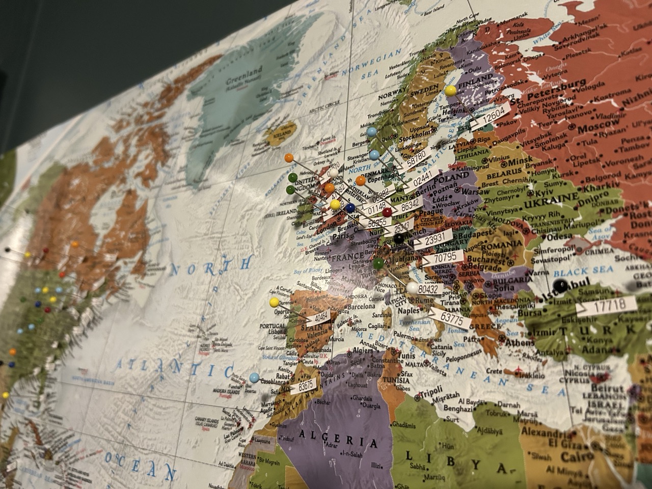 a photo of a world map with different small numbers pinned to various cities